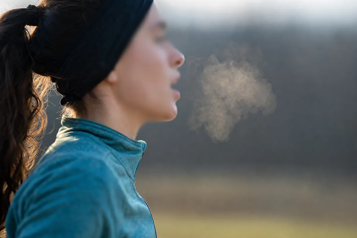 Gros plan sur le profil d&rsquo;une coureuse en effort, bouche entrouverte, expiration visible dans l&rsquo;air frais